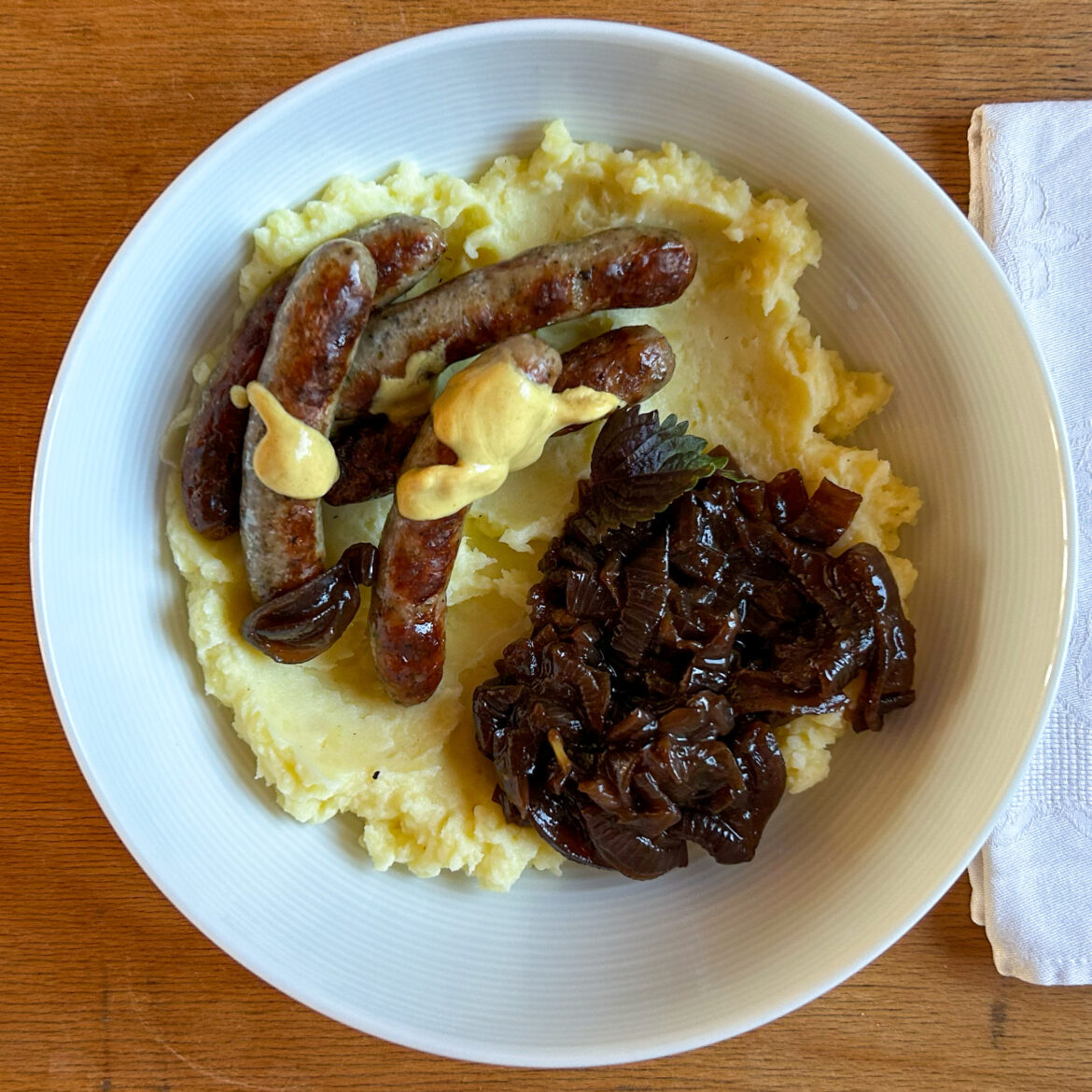 Bratwurst an Kartoffelstampf mit geschmelzten Zwiebeln