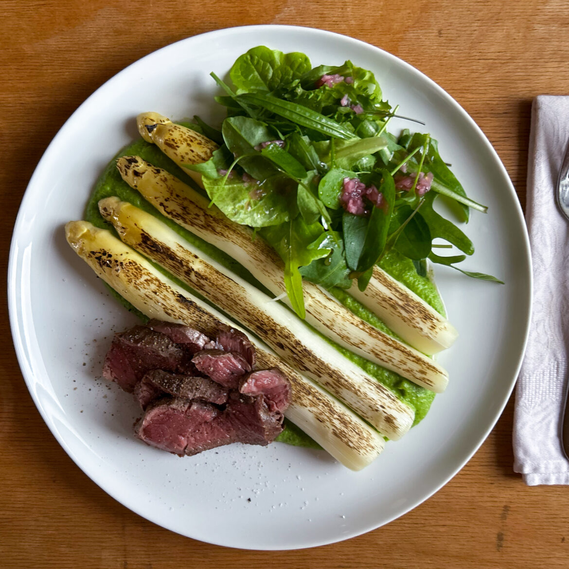 Geflammter sous-vide Spargel an Rinderfilet und Erbsenpüree mit Wasabiblatt und Wildkräutersalat